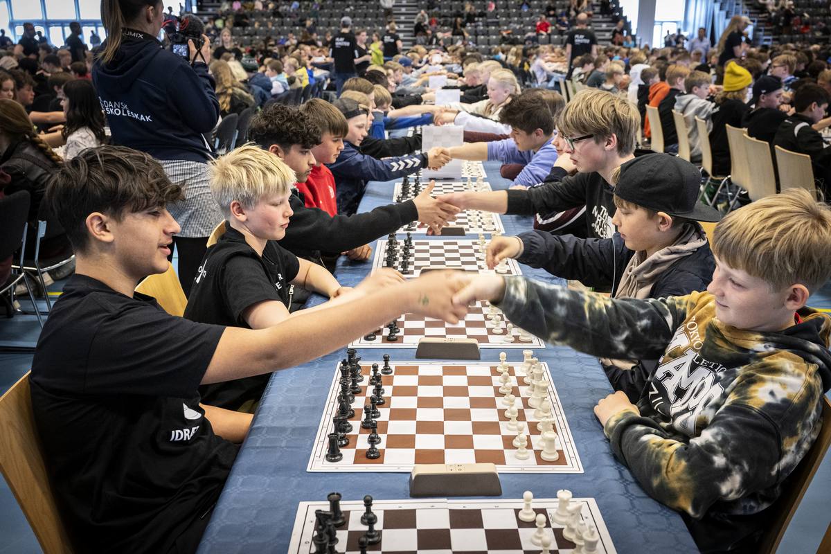 Børn giver hånd over skakbræt